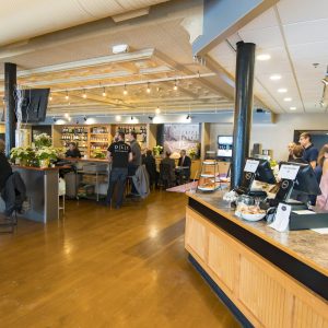 groups of people sit around tables at the new cafe with wood floors and exposed bulb light fixtures