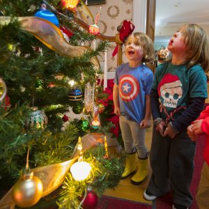 Three kids look at a Christmas tree in awe